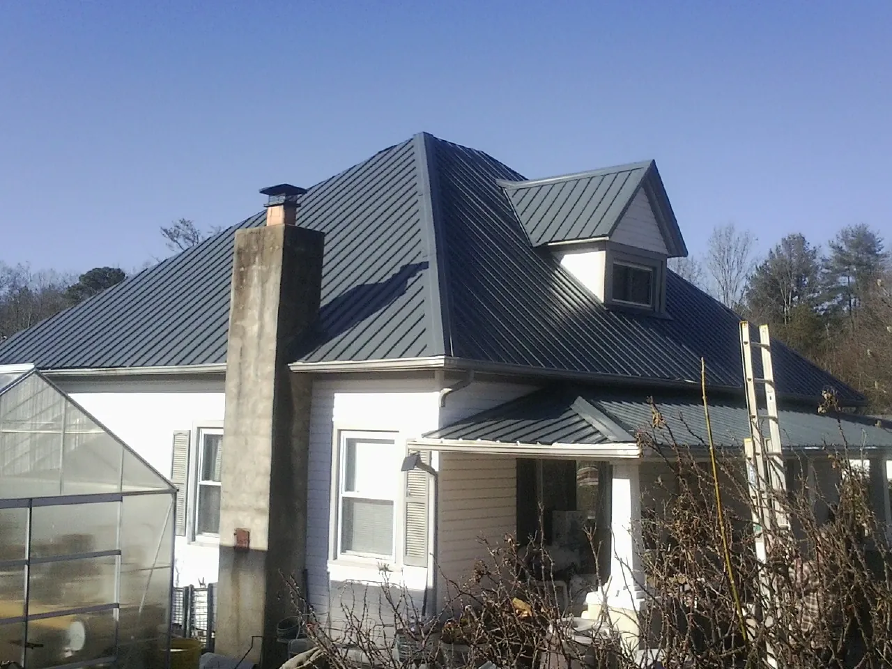 Dark blue standing seam metal roof on a white farmhouse with dormer — Slate & Tile Roof Repair by Roofing Brothers in Raywood