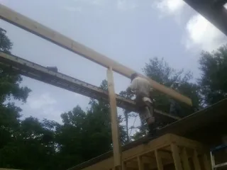 Carpenter setting a ridge beam over a new addition frame — Ice Dam Removal by Roofing Brothers in Raywood