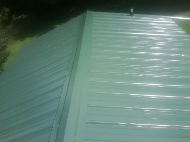 New green metal panels meeting at the ridge of a roof — Flat Roof Repair work by our crew in Raywood