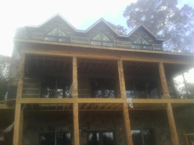 Dormers and porch framing on a large log home under construction — Roof Coating work by our crew in Raywood