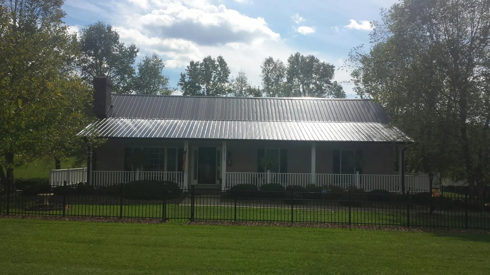 Gray metal roof on a brick ranch with a full width front porch — Gutter Guard Installation work by our crew in Raywood
