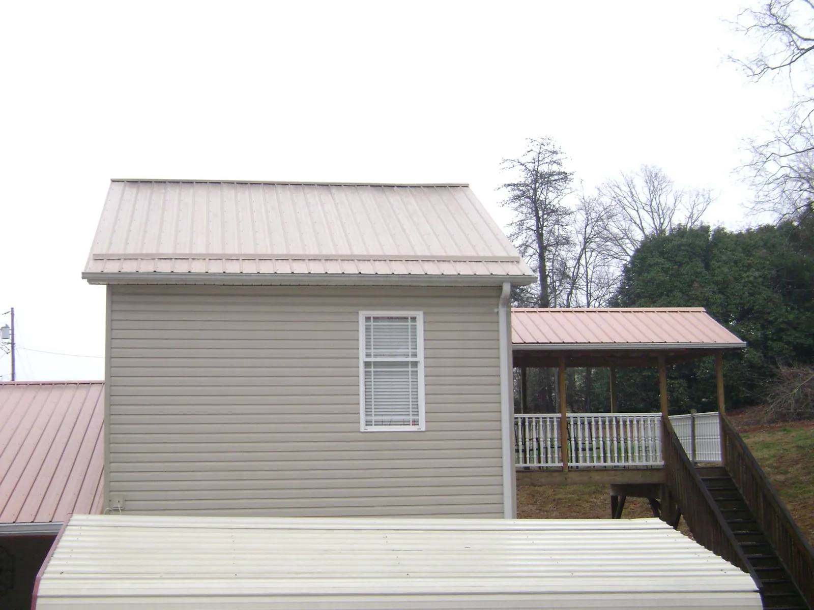 Tan metal roofs on a two story addition and attached porch, from a Roof Replacement job in Raywood